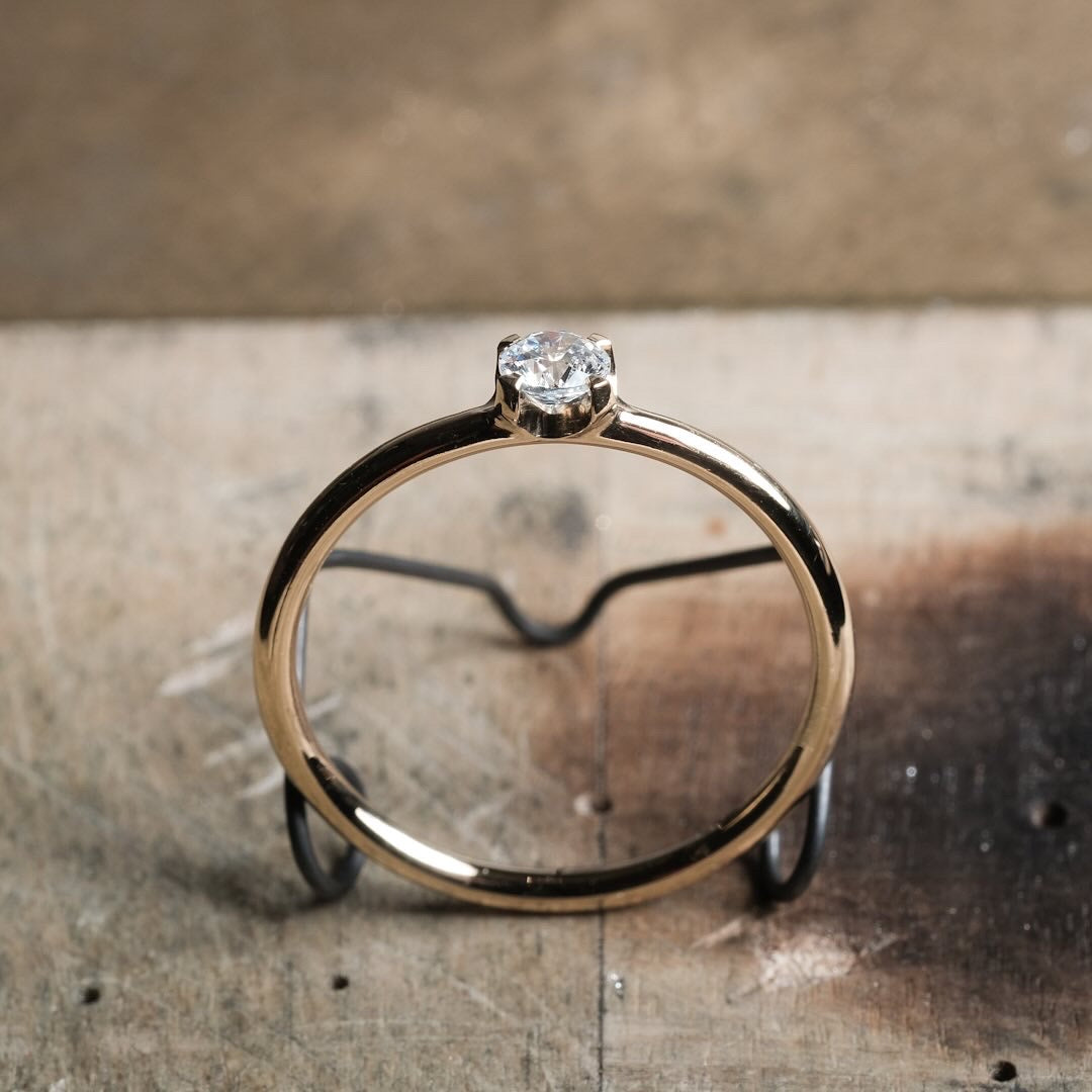 Das Foto Zeit einen Brillantring aus Gelb Gold, welcher einen Brillanten in einer vier krappen Fassung beeinhaltet.
Der Ring ist poliert. Das Bild zeigt den Ring von der Seite in Nahaufnahme.