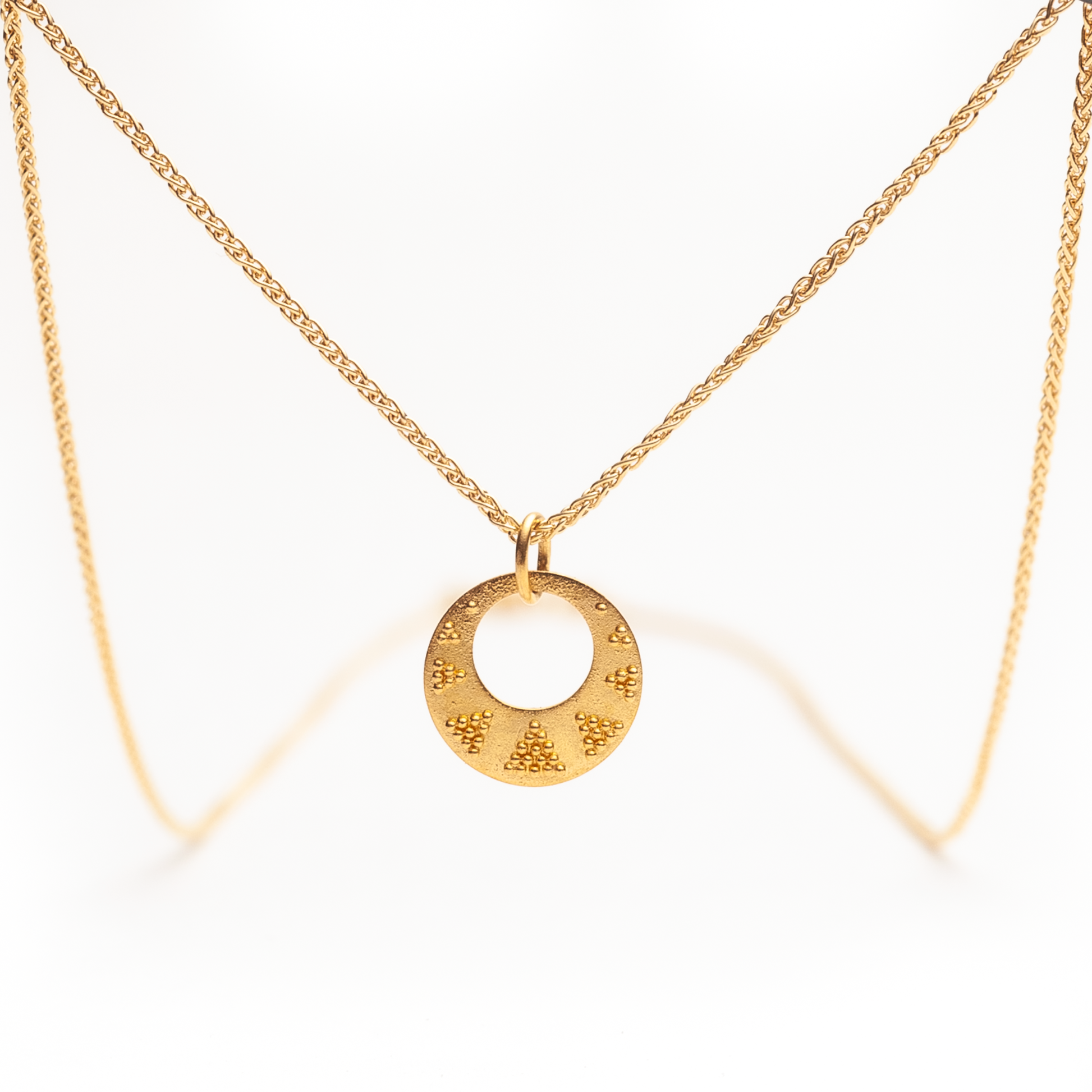 Granulierter Kettenanhänger, hängend präsentiert an einer feinen Zopfkette.