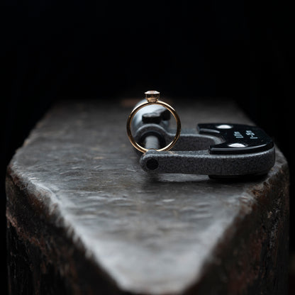Der Ring stehend auf einem massiven Amboss. Gehalten von einer Mikrometermessschraube.